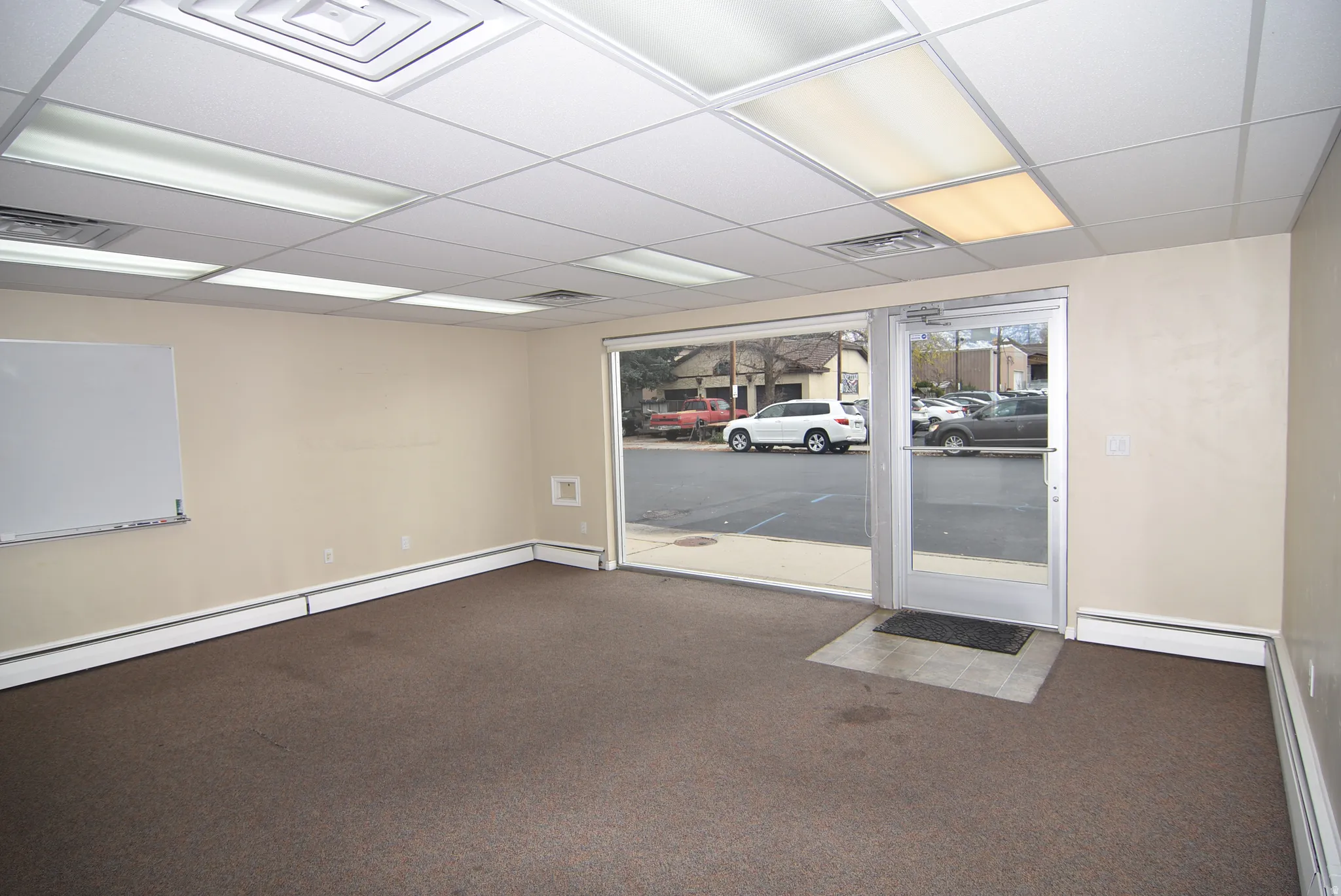 Spare room with carpet flooring, a baseboard heating unit, and a drop ceiling