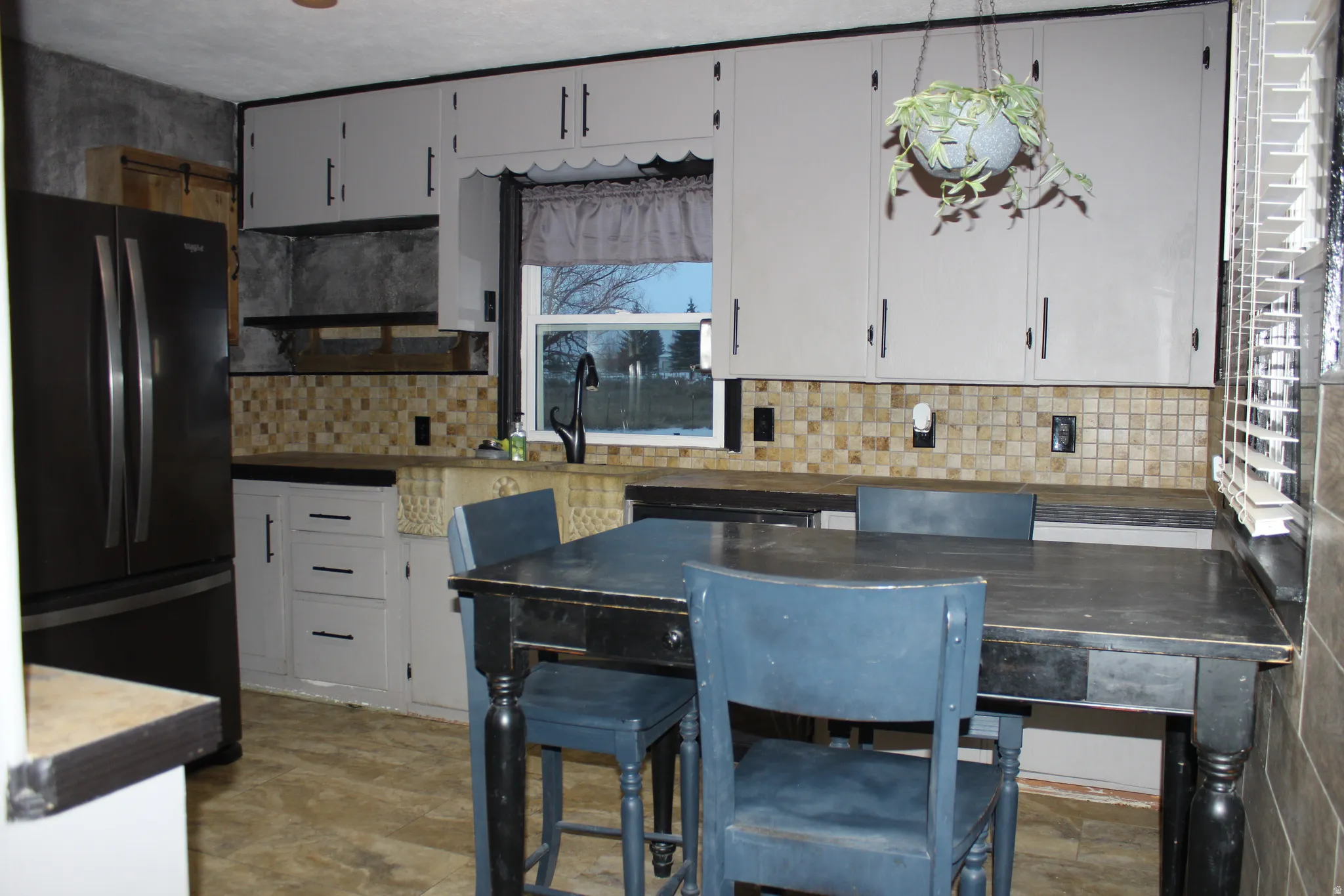 Kitchen featuring freestanding refrigerator, backsplash, and white cabinets