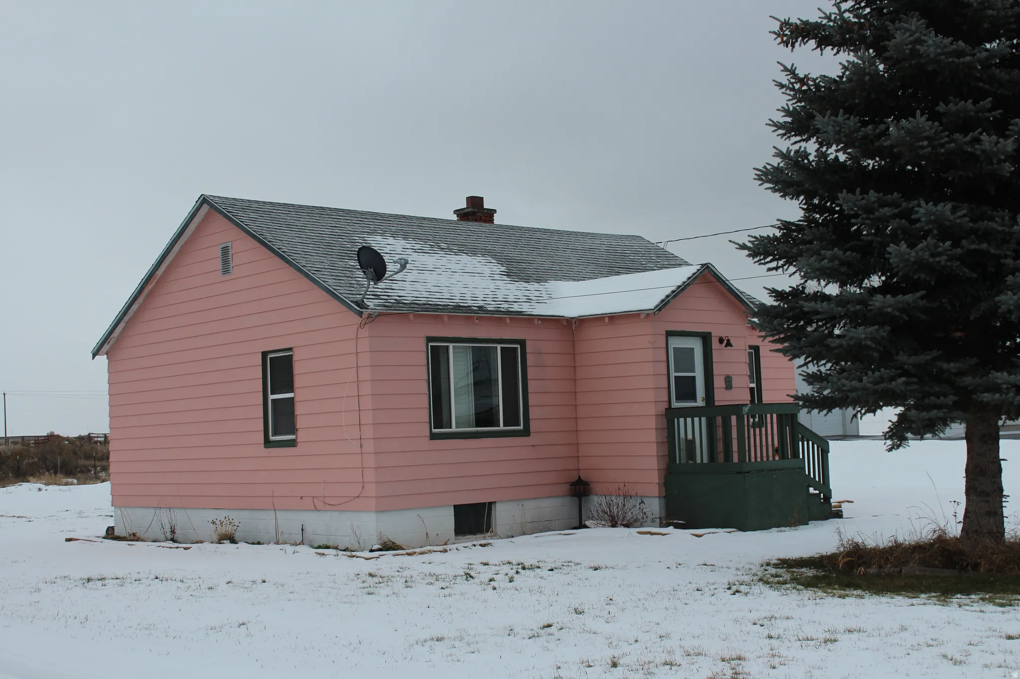 View of snowy exterior featuring a chimney and roof with shingles