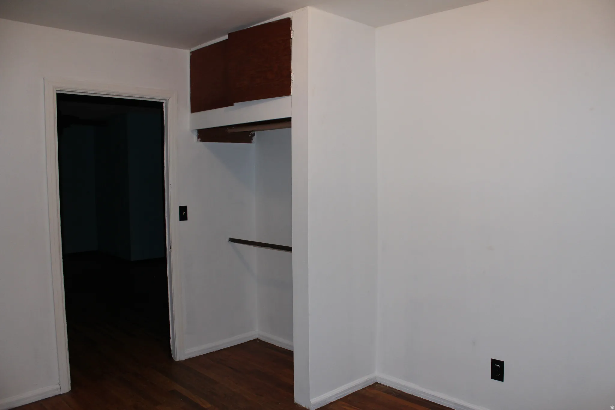 Spare room with dark wood-type flooring and baseboards