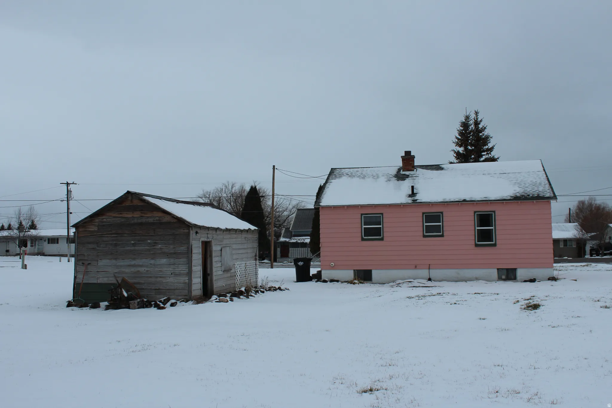 Snow covered back of property featuring a chimney and an outbuilding