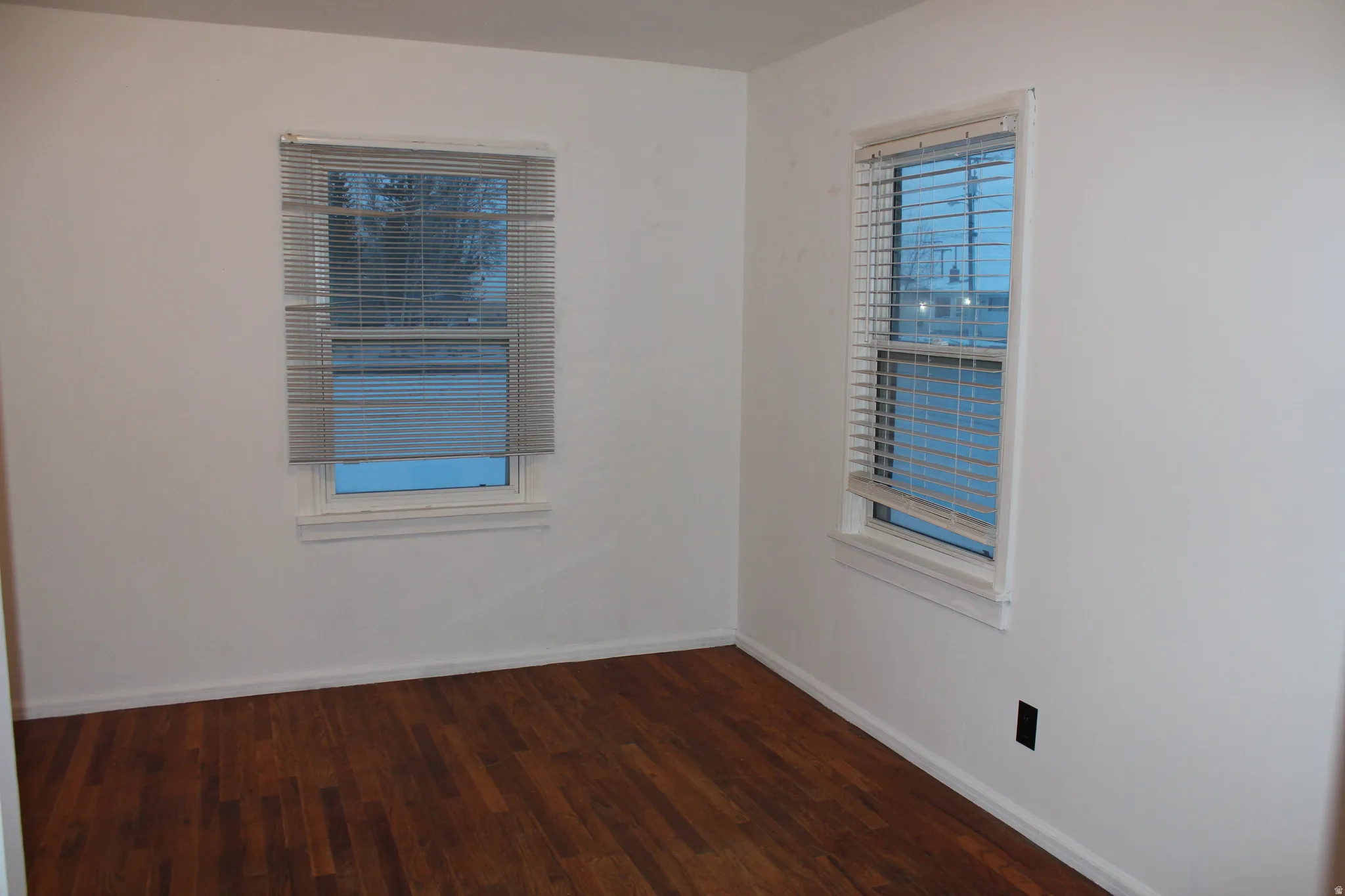 Empty room featuring dark wood-style flooring and baseboards