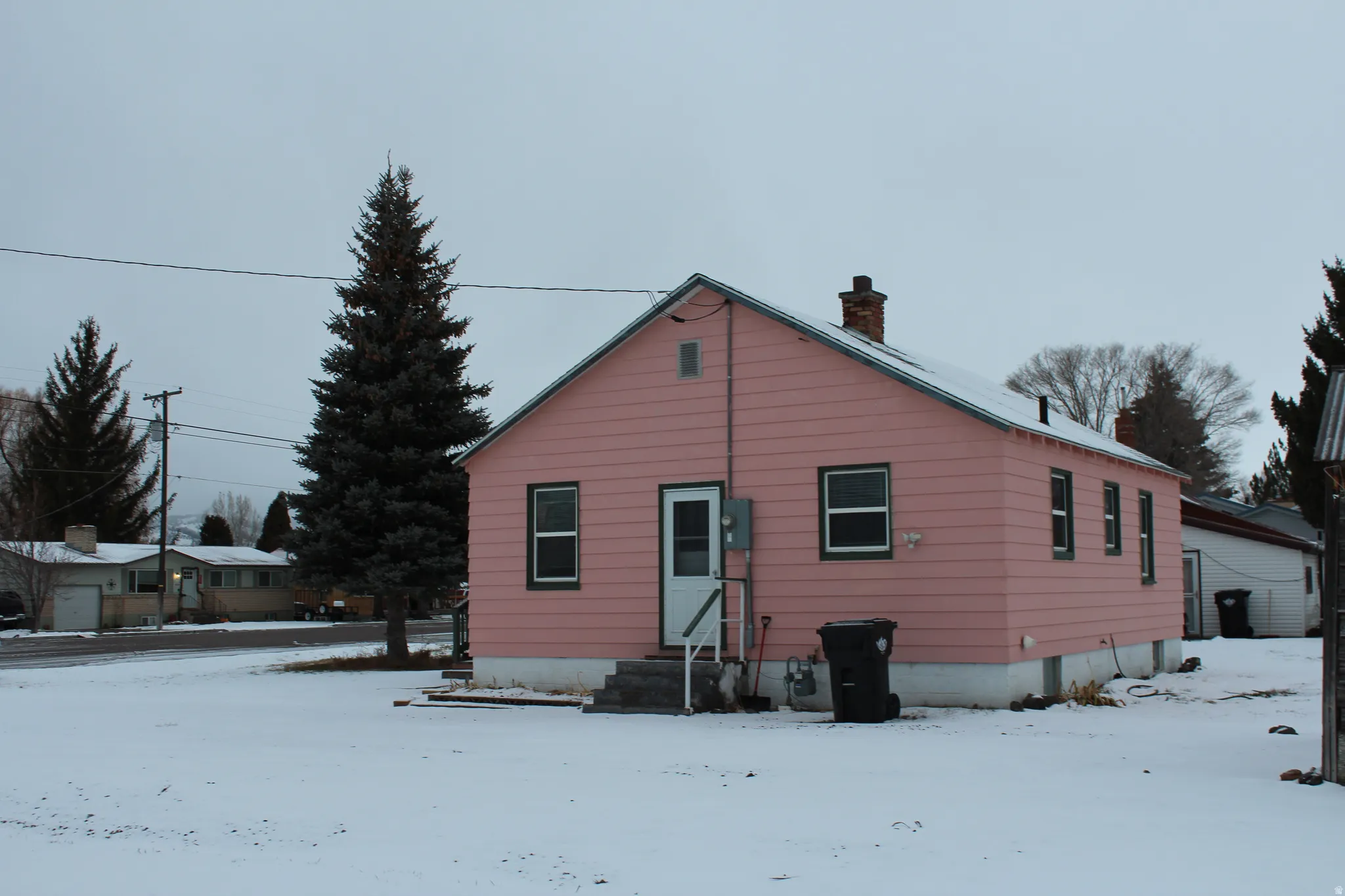 Snow covered house with a chimney and entry steps