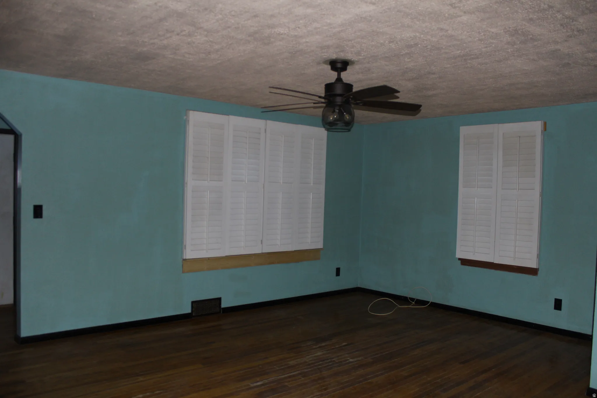 Spare room featuring dark wood-type flooring, a ceiling fan, and a textured ceiling