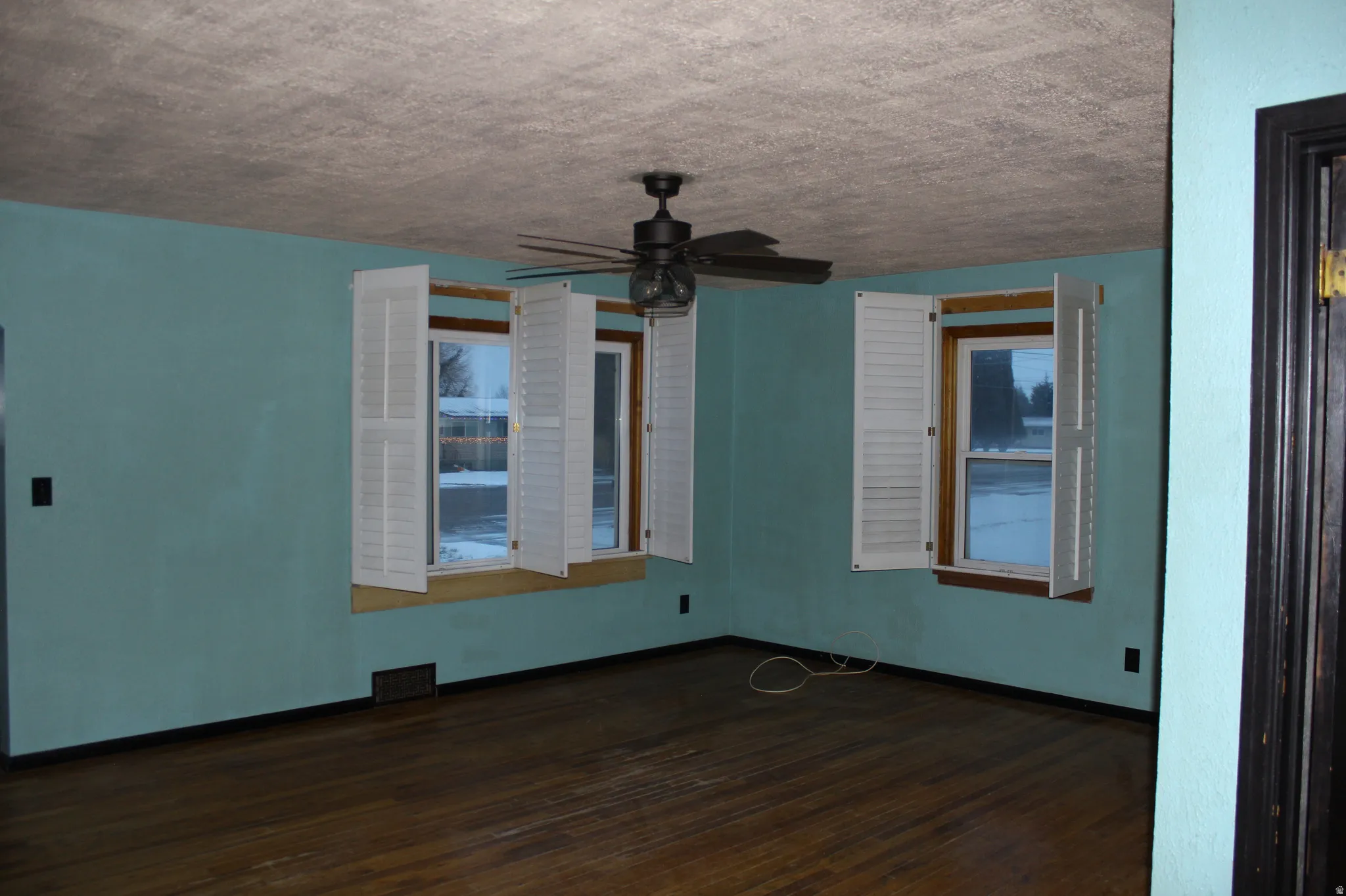 Empty room featuring dark wood finished floors, a textured ceiling, and a ceiling fan