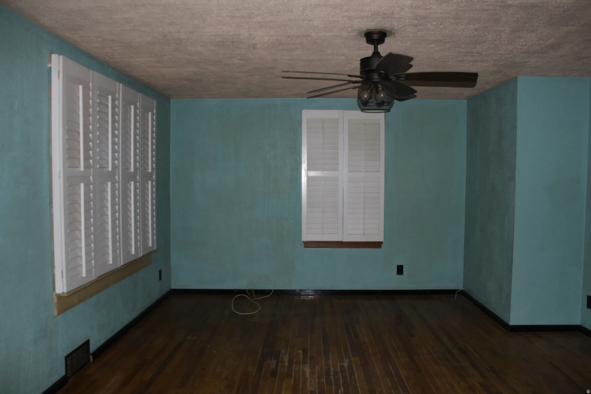 Spare room featuring dark wood-style flooring, mail area, and a textured ceiling