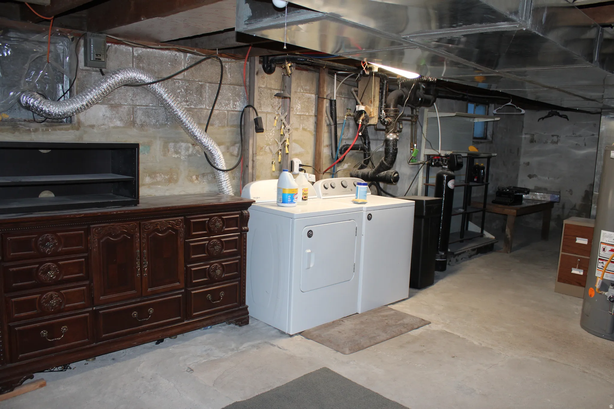 Unfinished below grade area featuring washer and clothes dryer and gas water heater
