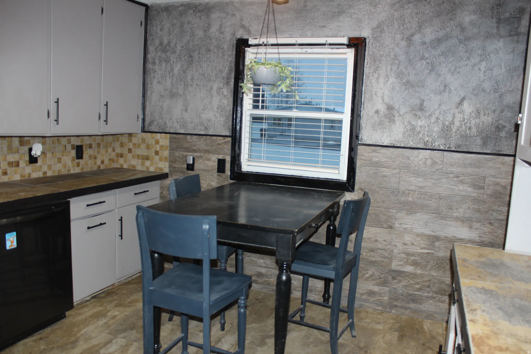 Kitchen with dishwasher, white cabinets, tile countertops, and tasteful backsplash
