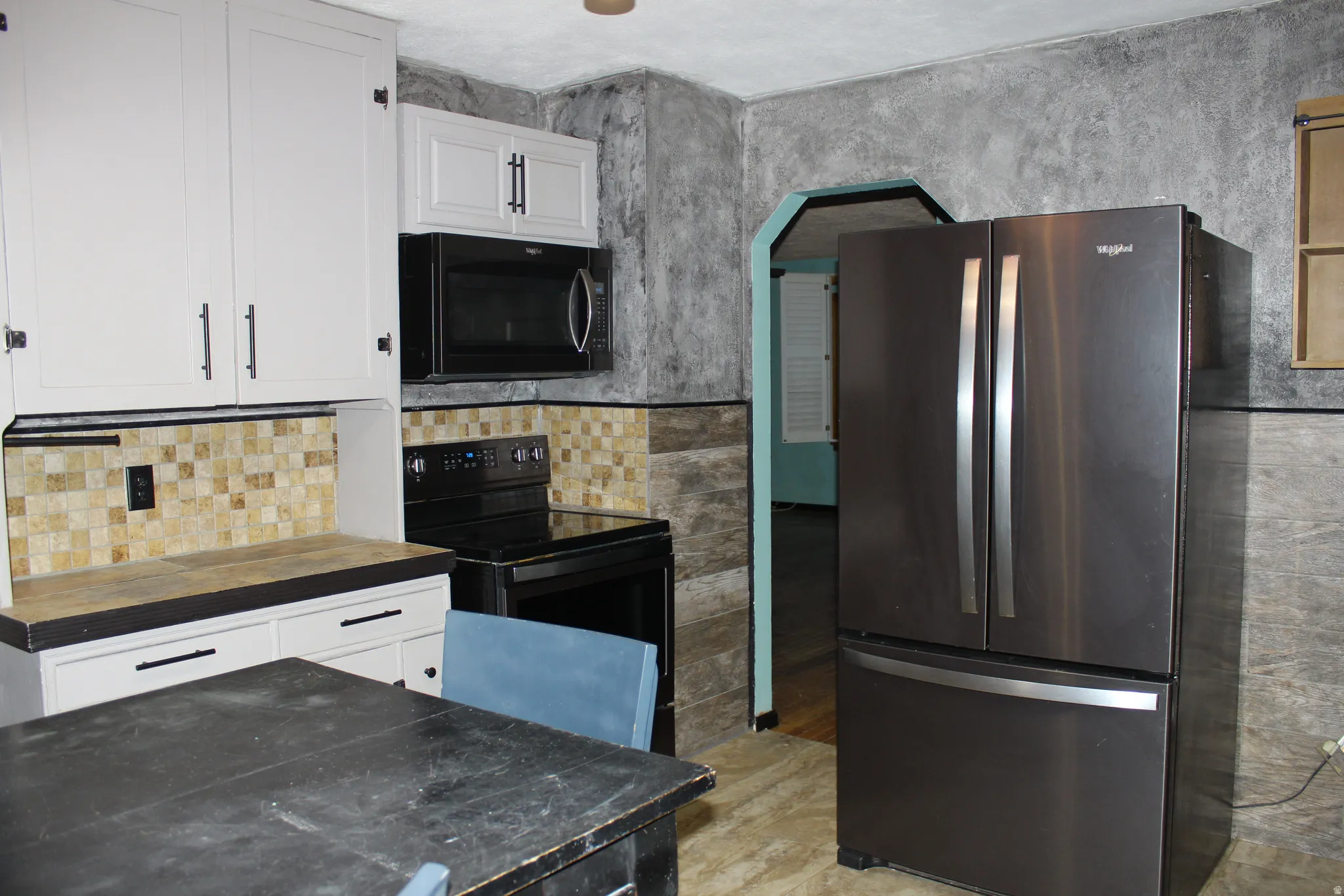 Kitchen featuring black appliances, white cabinets, and arched walkways