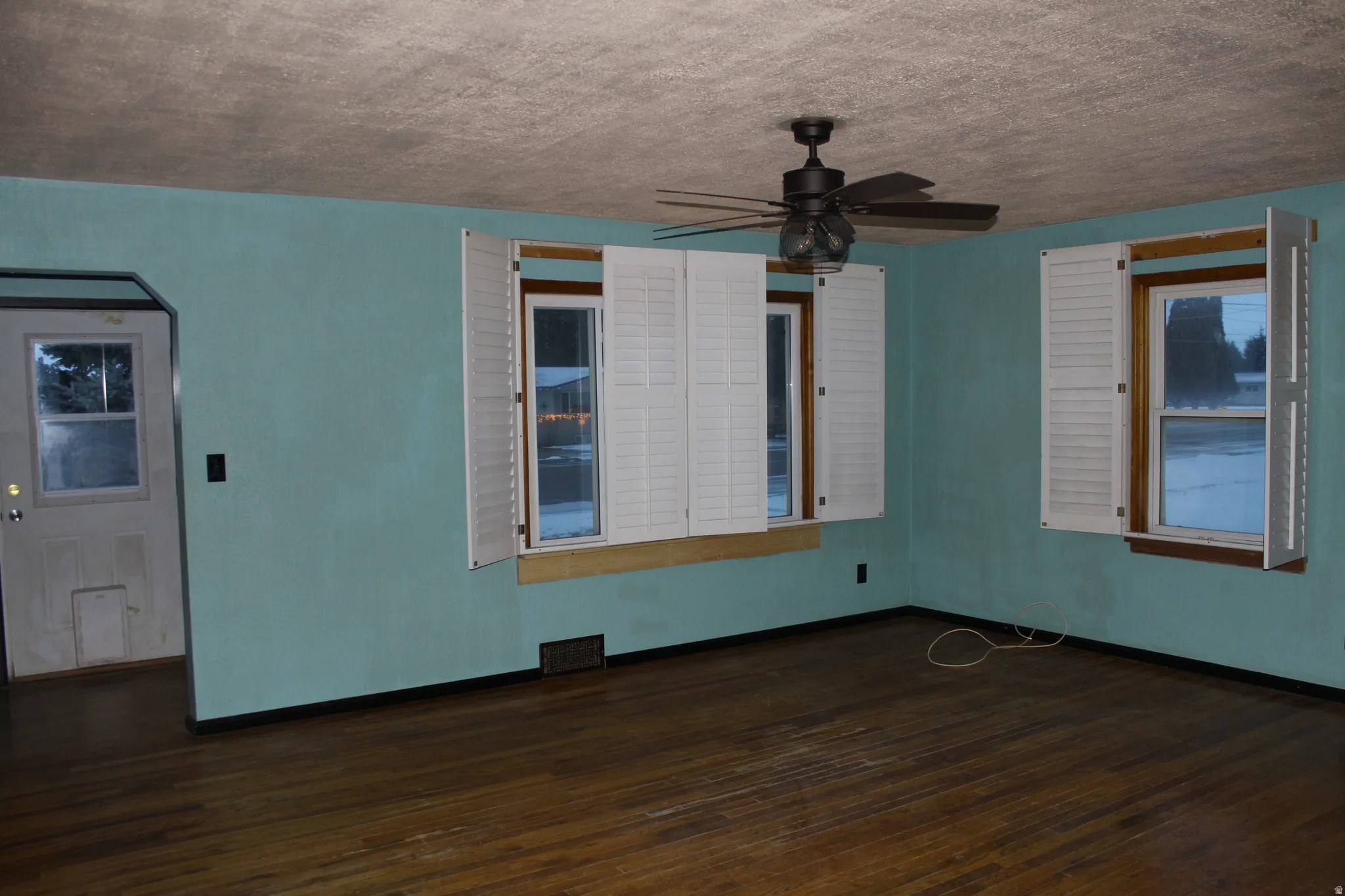 Unfurnished room featuring dark wood-type flooring, a ceiling fan, and a textured ceiling