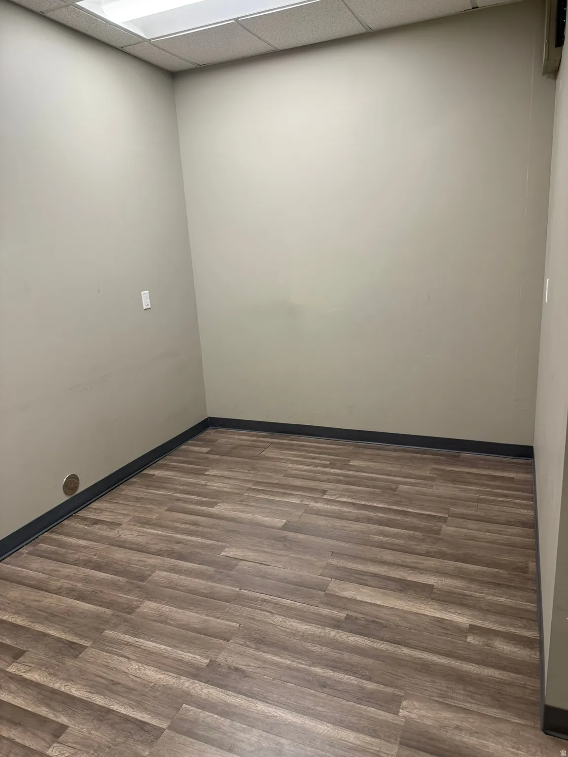 Empty room with wood finished floors and a drop ceiling