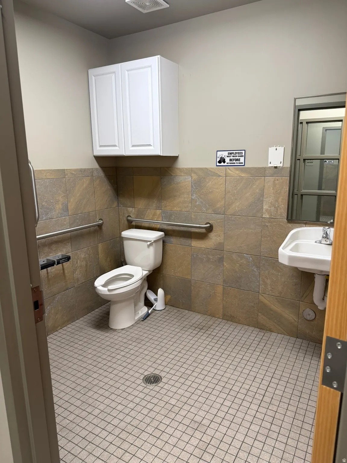 Half bath with tile patterned flooring, tile walls, and a wainscoted wall