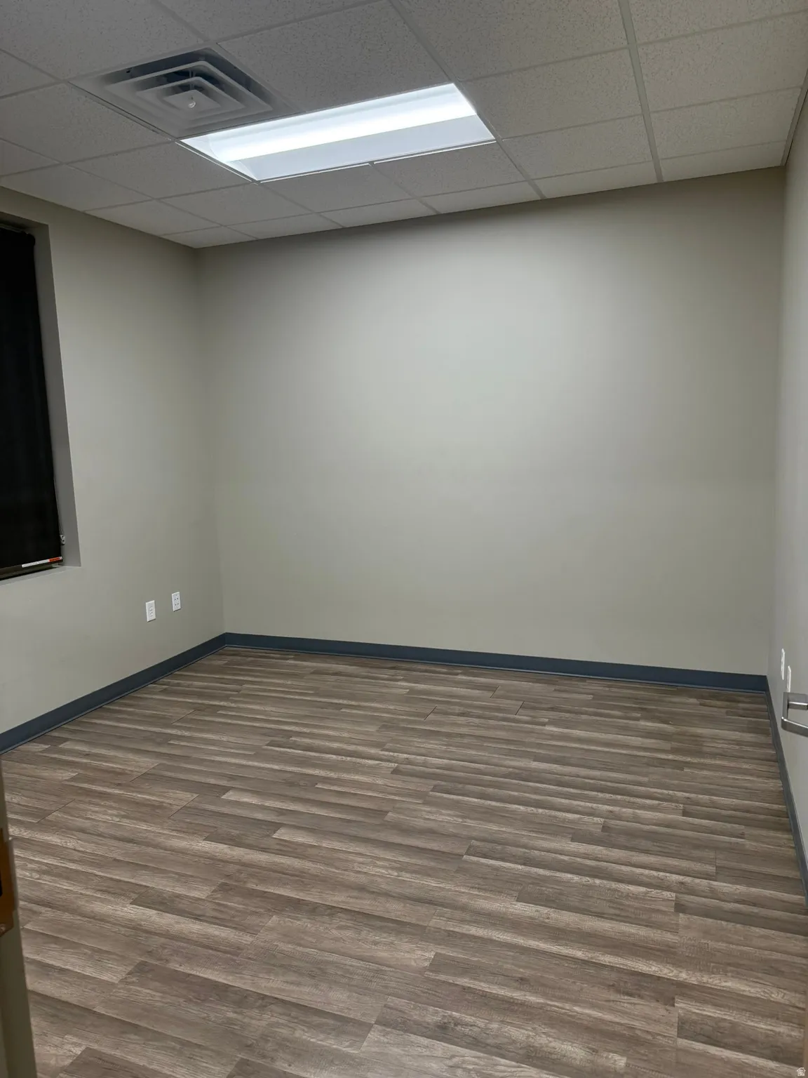 Unfurnished room featuring dark wood-style floors and a drop ceiling