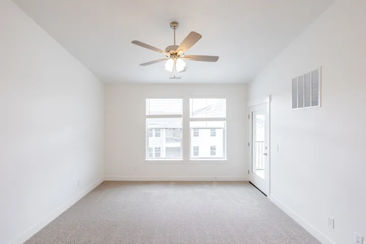 Room featuring light-colored carpeting, white walls, and a ceiling fan with integrated lighting