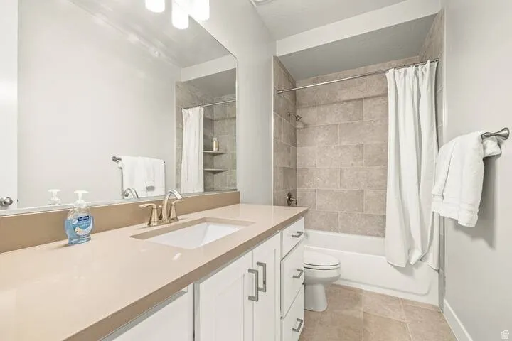 Bathroom featuring vanity, shower / bath combo, and light tile patterned floors