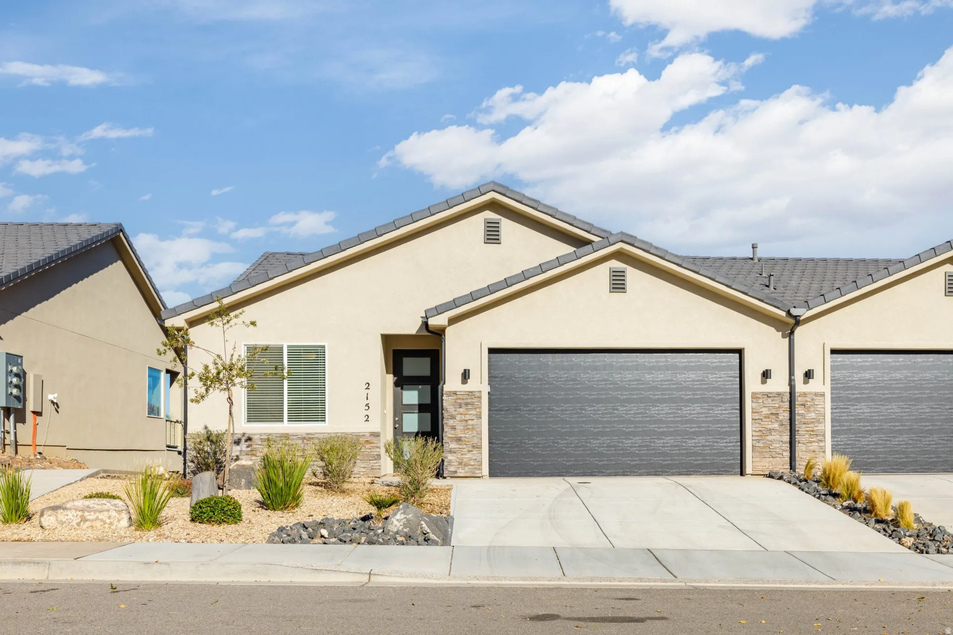 View of front of property featuring stone siding, stucco siding, driveway, and a garage