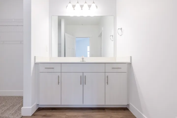 Vanity featuring a single-basin sink, light-toned countertop, and white cabinetry with brushed nickel hardware