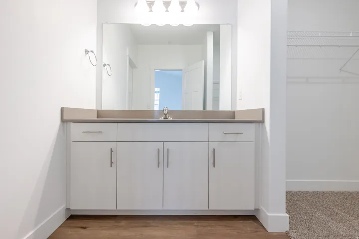 White vanity with a single basin sink, light-colored countertop, and chrome fixtures