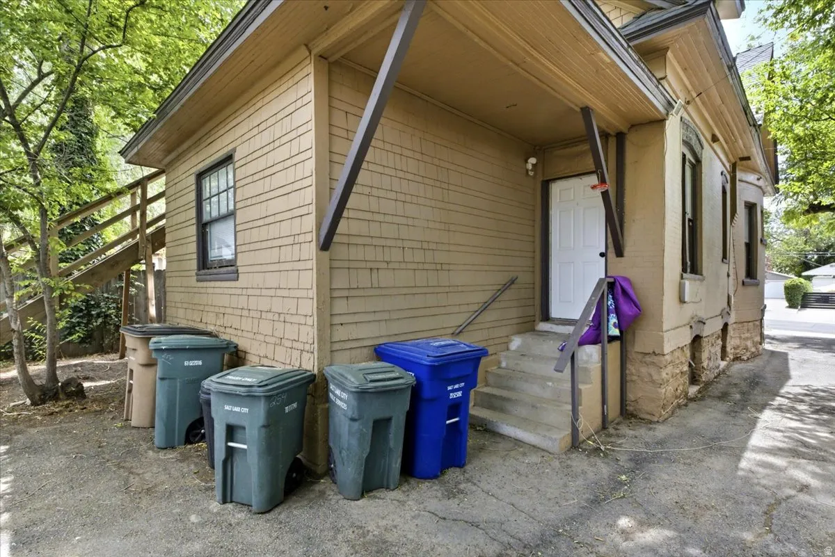 Rear exterior featuring wood shingle siding and a concrete stair entry with metal railings