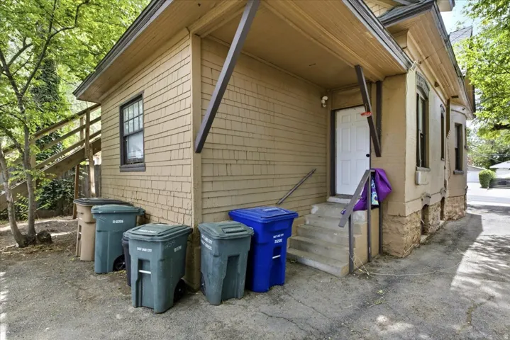 Rear exterior featuring wood shingle siding and a concrete stair entry with metal railings