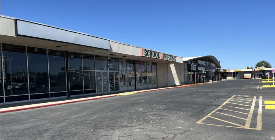 Retail storefront with expansive display windows, prominent signage area, and direct access to parking