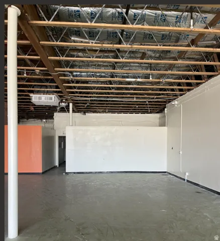 Exposed wood beam ceiling, open-concept layout, concrete flooring, painted interior walls, and central support column