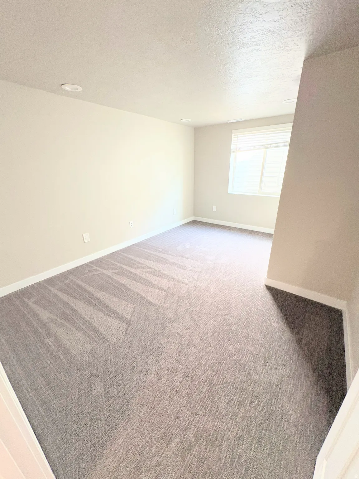 Empty room with light colored carpet and a textured ceiling