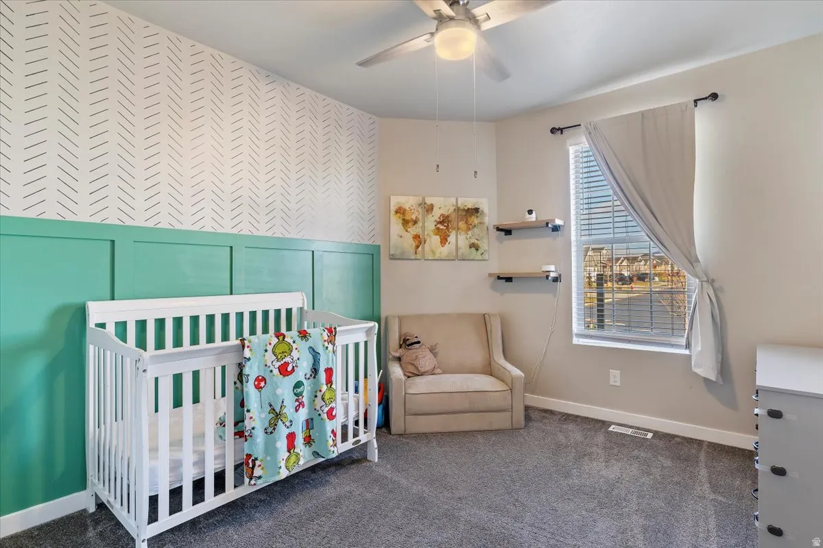 Bedroom with a decorative wall, a nursery area, an accent wall, wallpapered walls, and carpet