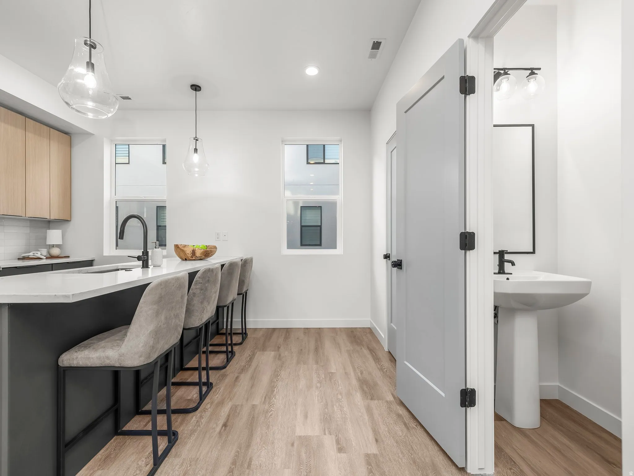 Kitchen featuring a breakfast bar, decorative light fixtures, light brown cabinetry, light wood-type flooring, and a peninsula