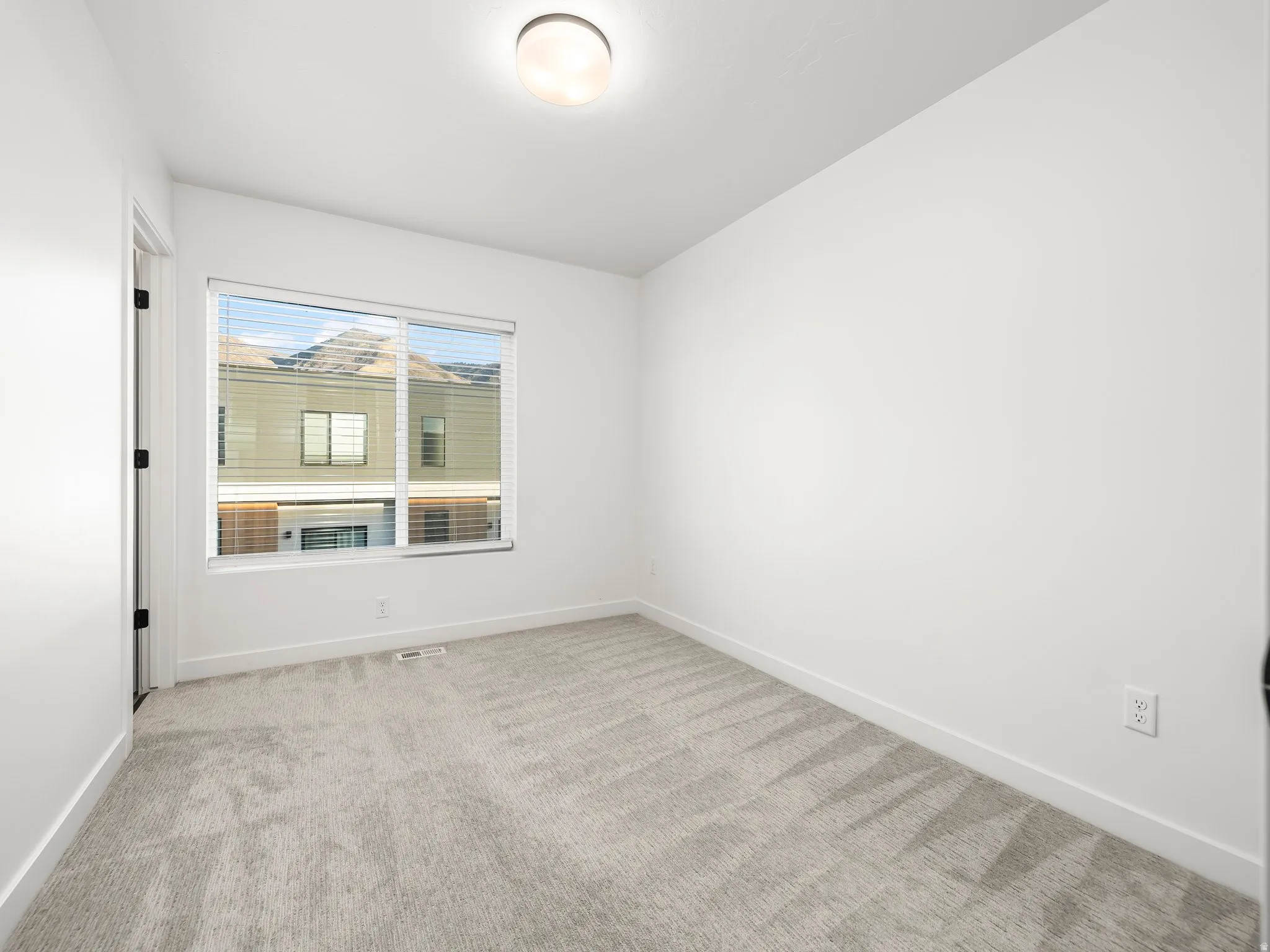 Unfurnished room featuring light colored carpet and baseboards