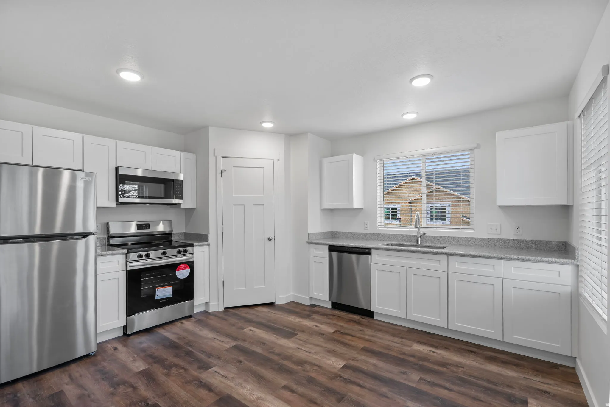 Kitchen featuring stainless steel appliances, white cabinetry, and dark wood-style floors