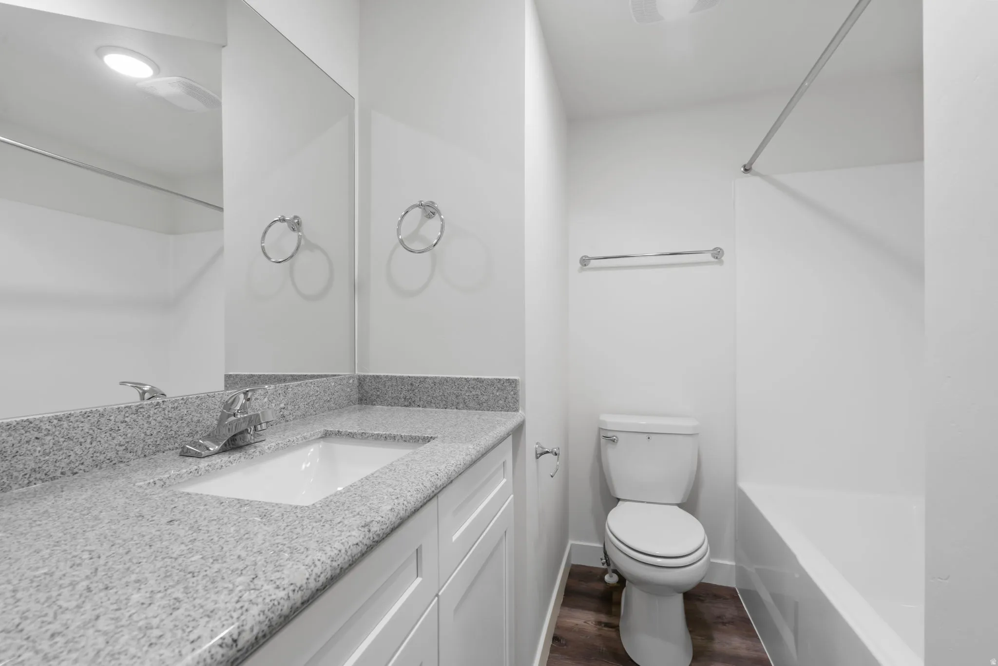 Bathroom featuring vanity, tub / shower combination, and dark wood-style floors
