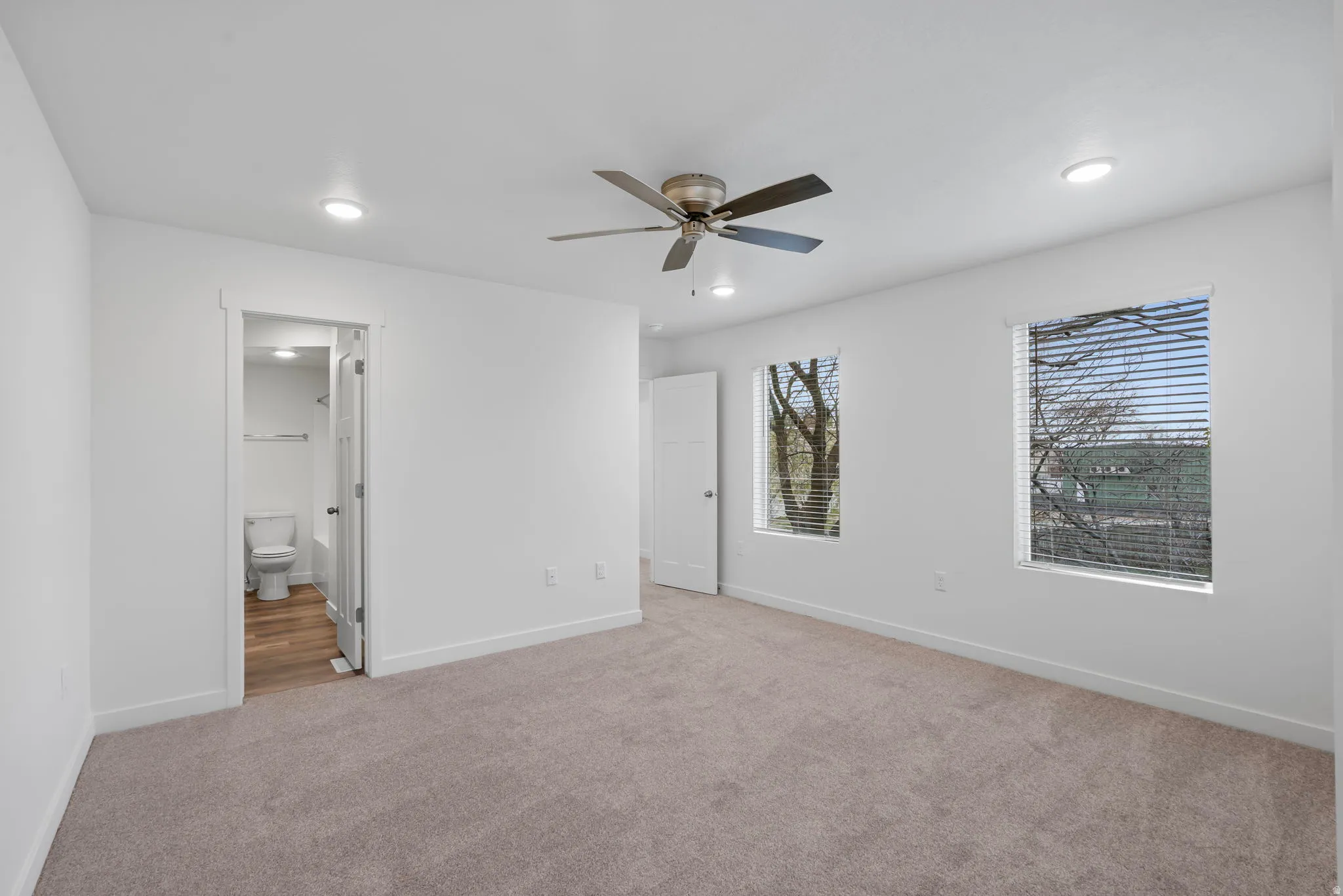 Unfurnished bedroom with light carpet, a ceiling fan, recessed lighting, and ensuite bathroom