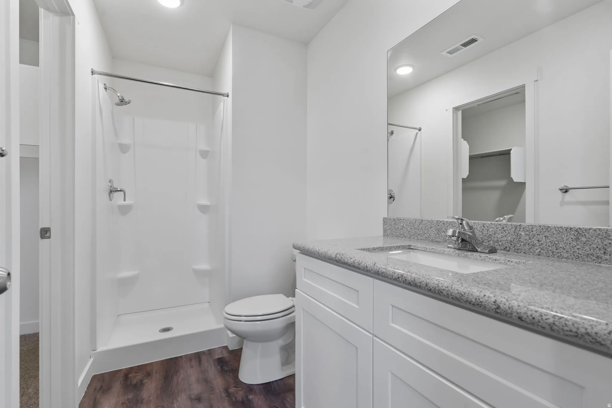 Bathroom with a spacious closet, vanity, dark wood-style floors, a stall shower, and recessed lighting