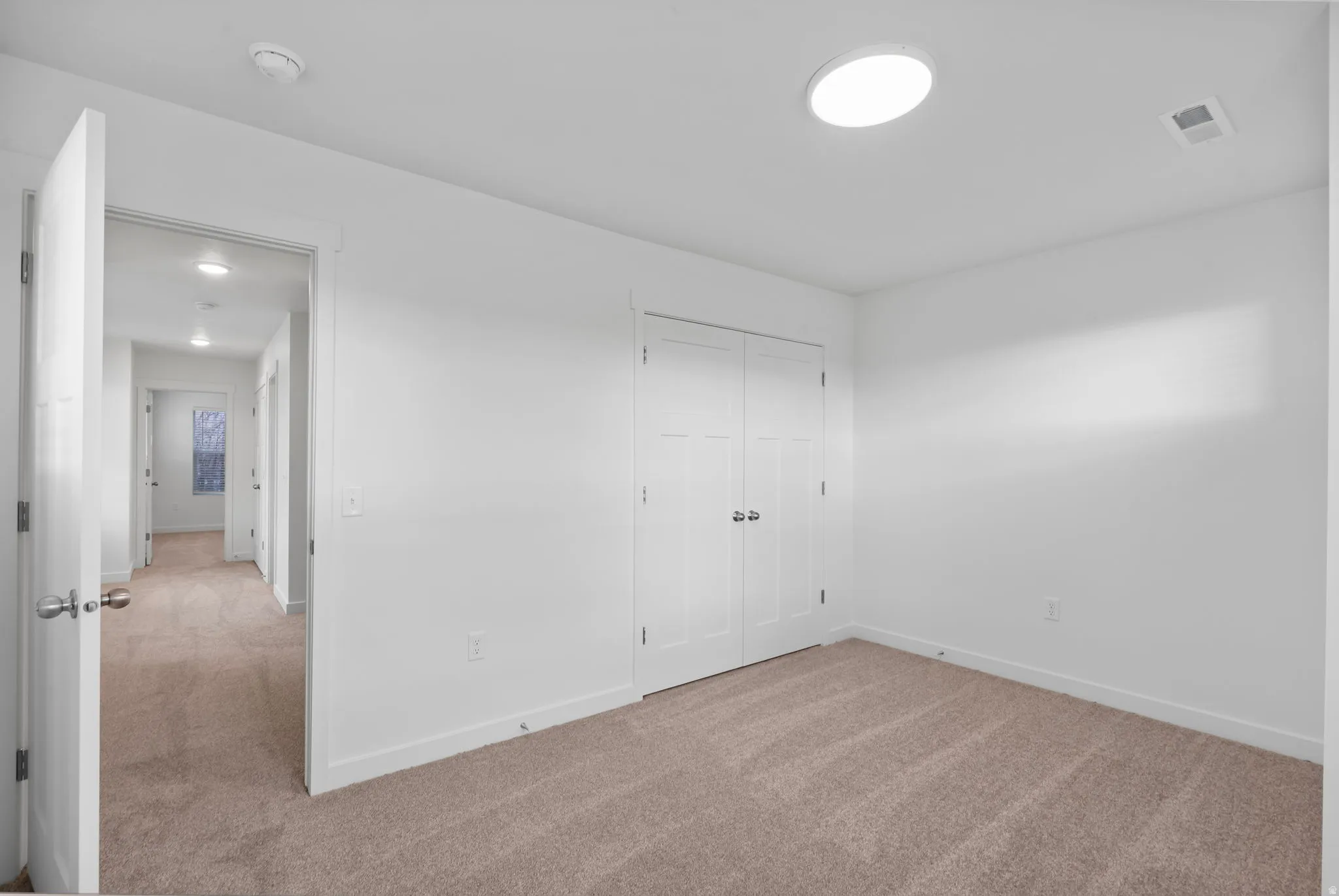 Unfurnished bedroom featuring light carpet and a closet