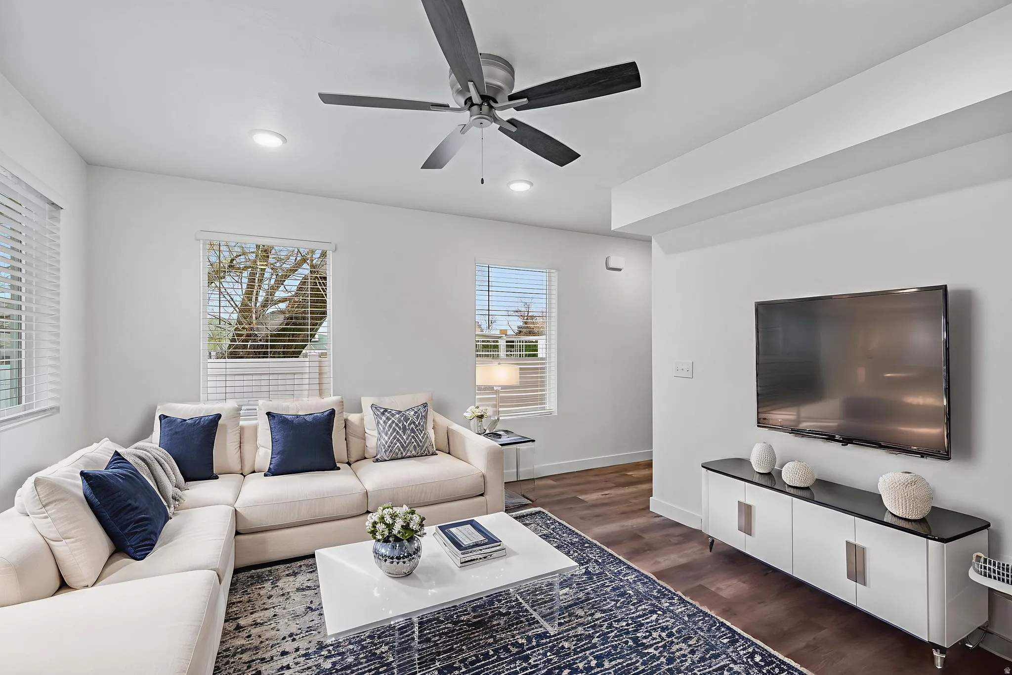 Living area with dark wood-type flooring, a ceiling fan, and recessed lighting