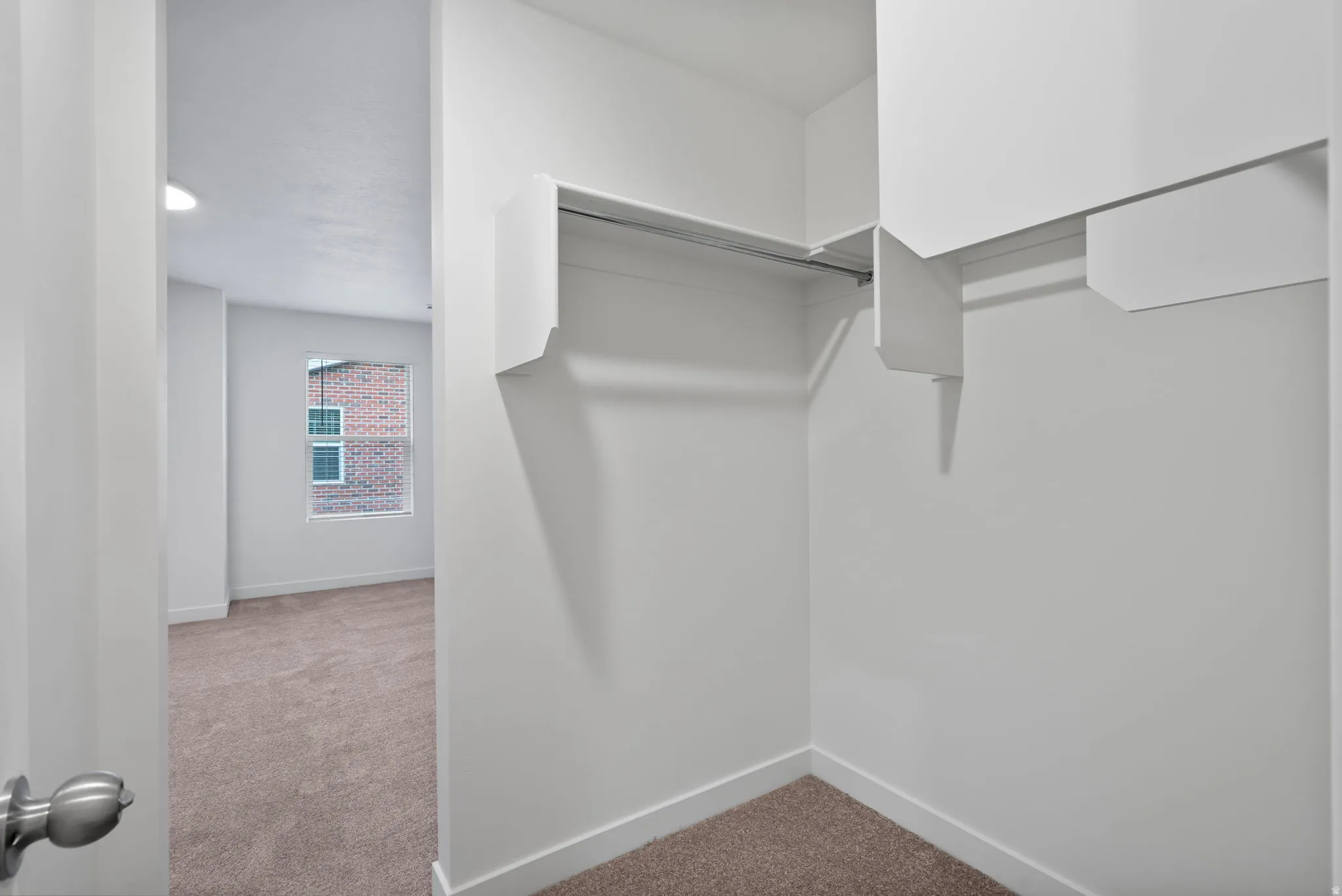 Walk in closet featuring light colored carpet