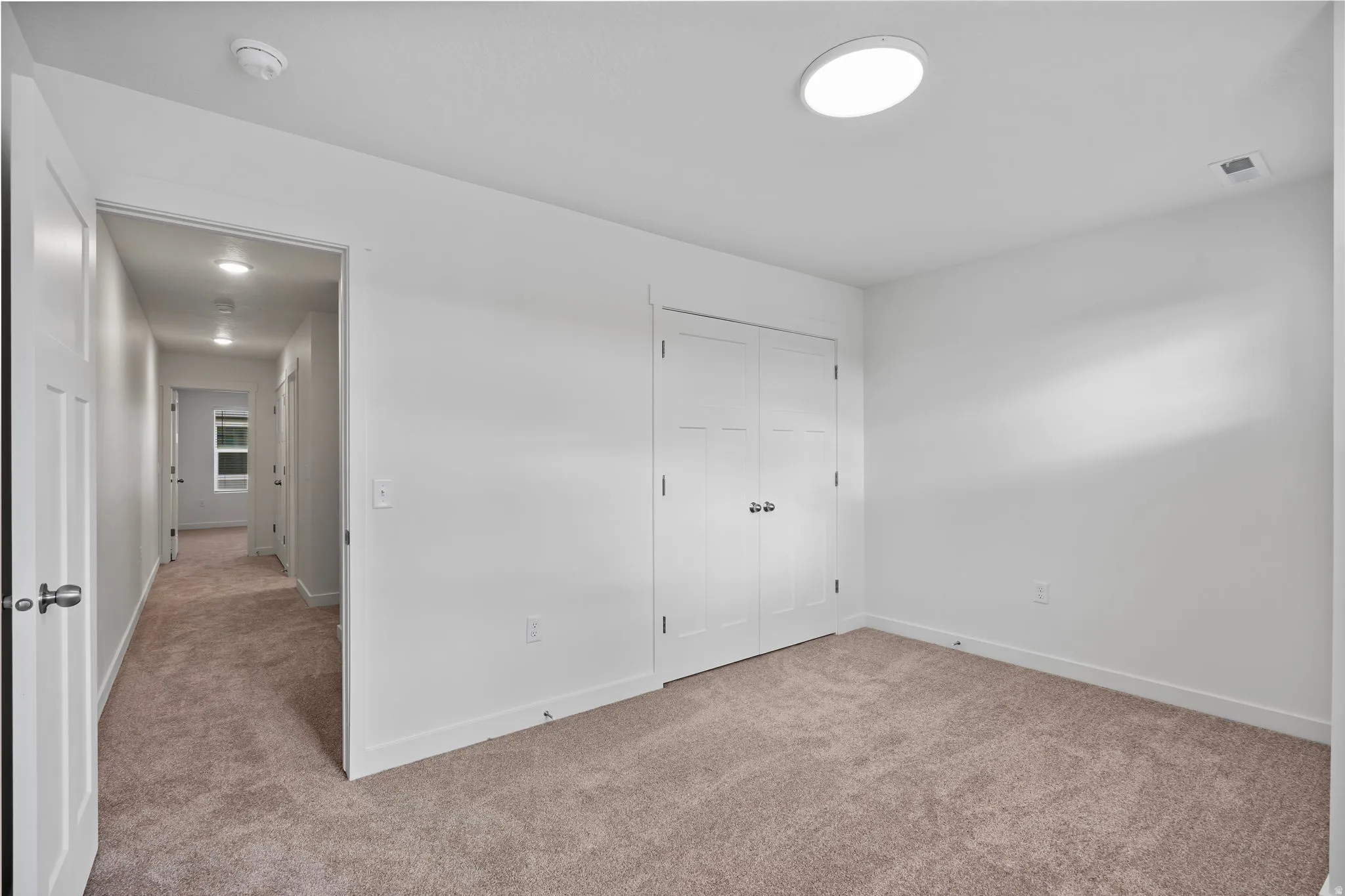 Unfurnished bedroom with light colored carpet and a closet