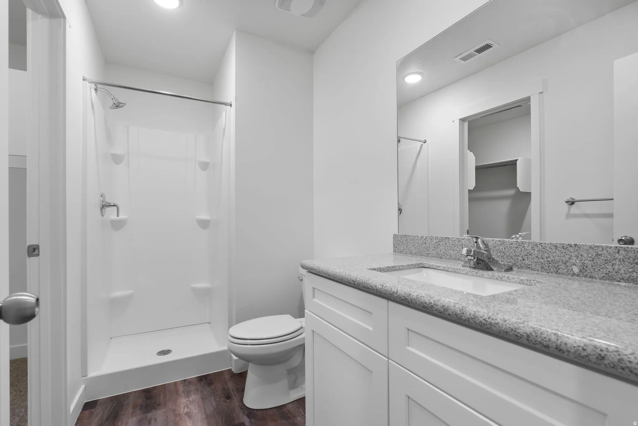 Full bathroom with vanity, a spacious closet, a shower stall, dark wood-type flooring, and recessed lighting