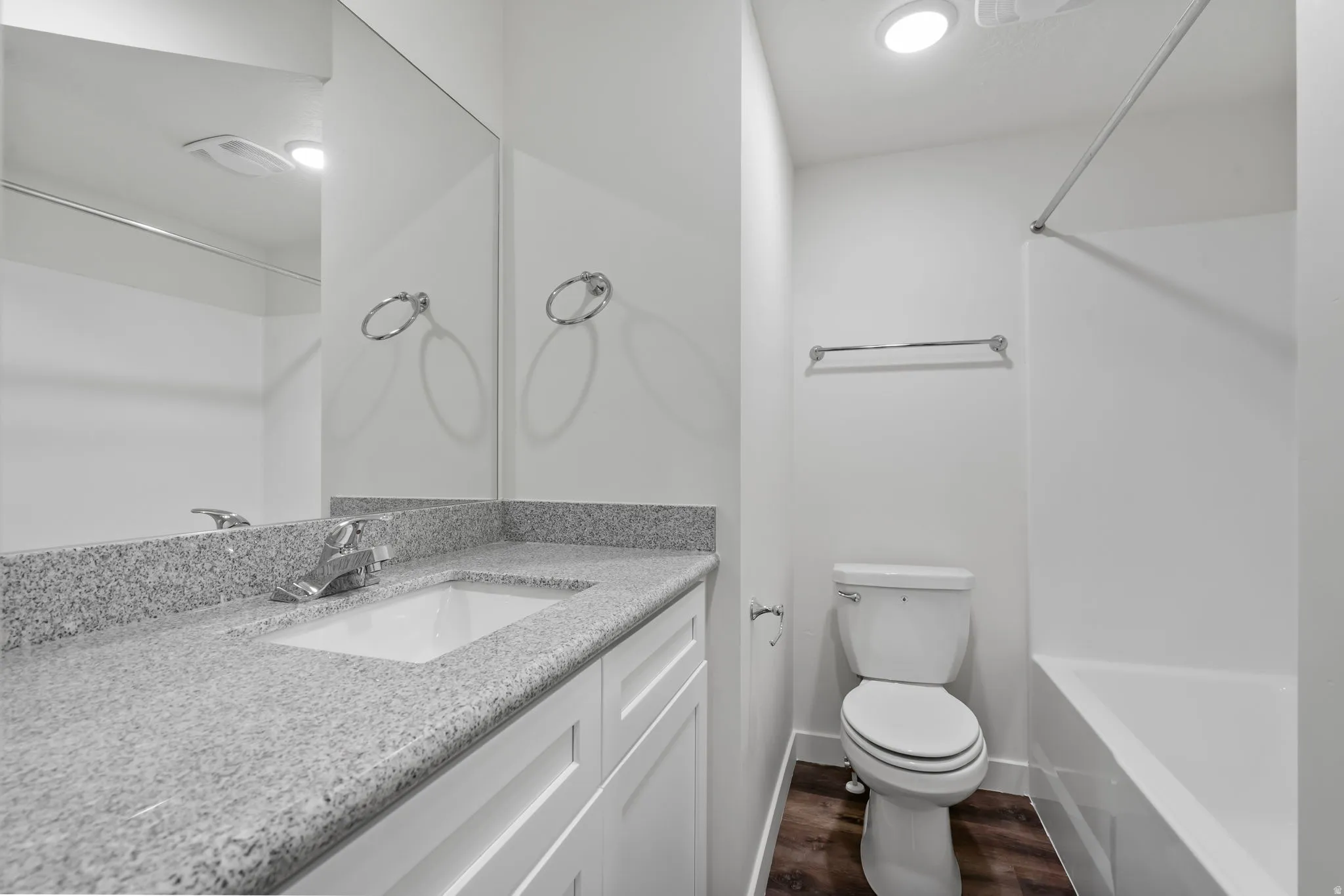 Bathroom with vanity, tub / shower combination, and dark wood-style floors