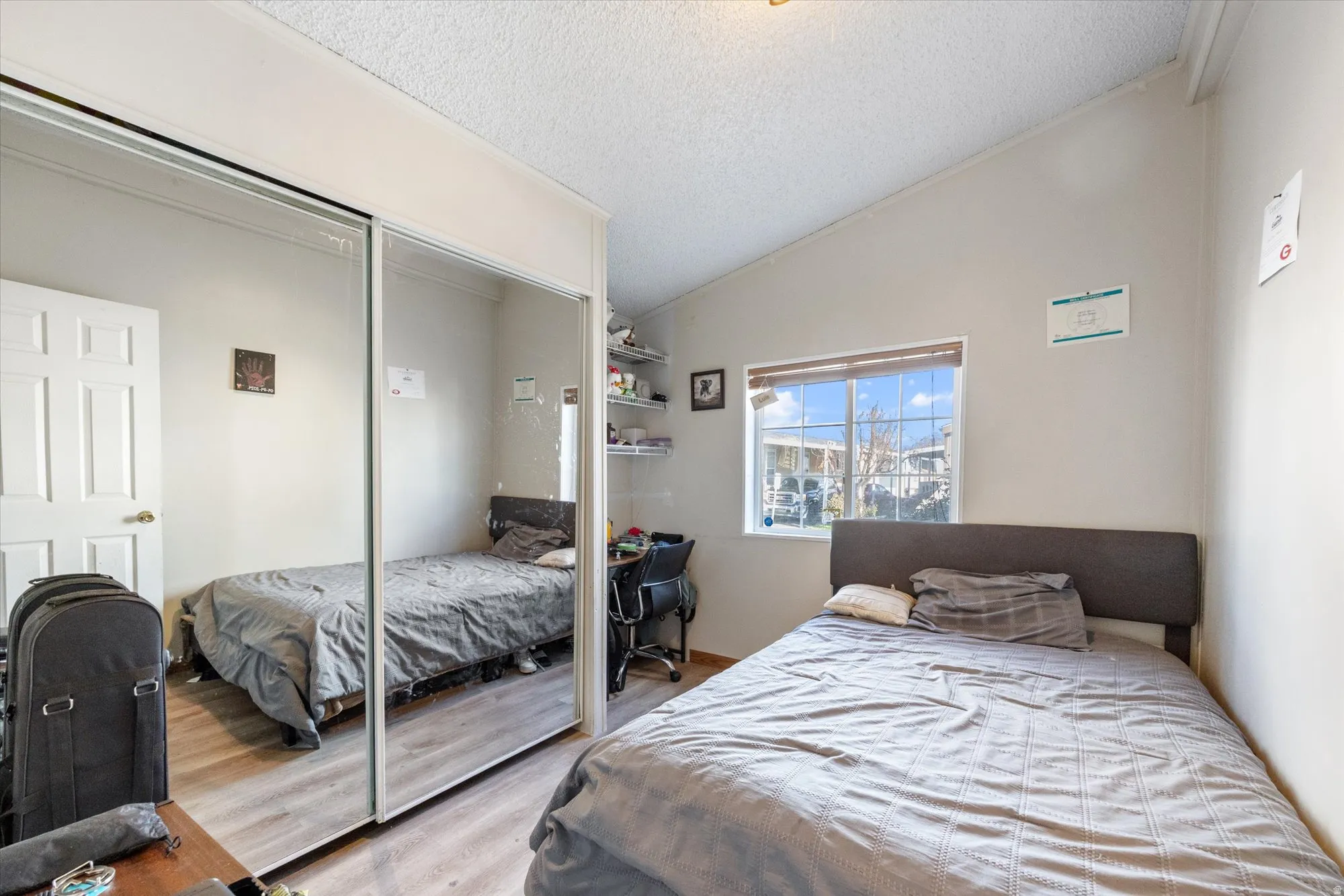 Bedroom with lofted ceiling, a textured ceiling, wood finished floors, and a closet