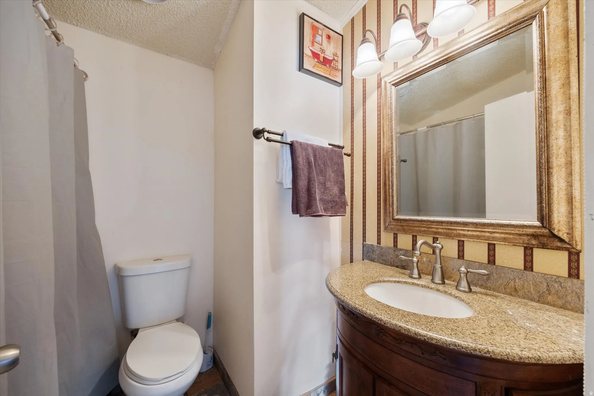 Full bath featuring a textured ceiling, vanity, and a shower with shower curtain