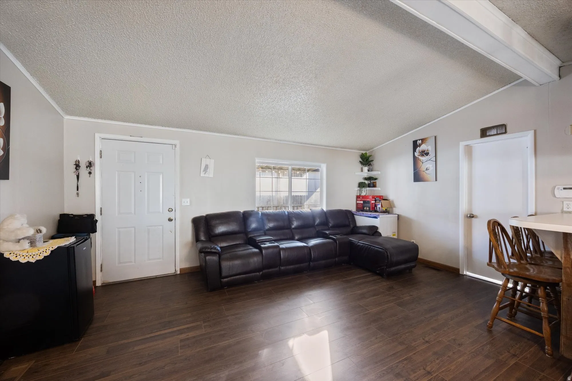 Living room featuring a textured ceiling, dark wood finished floors, and crown molding