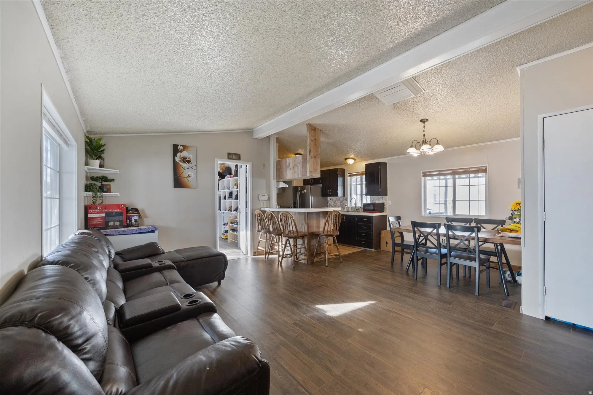 Living area featuring dark wood-style floors, a chandelier, and a textured ceiling