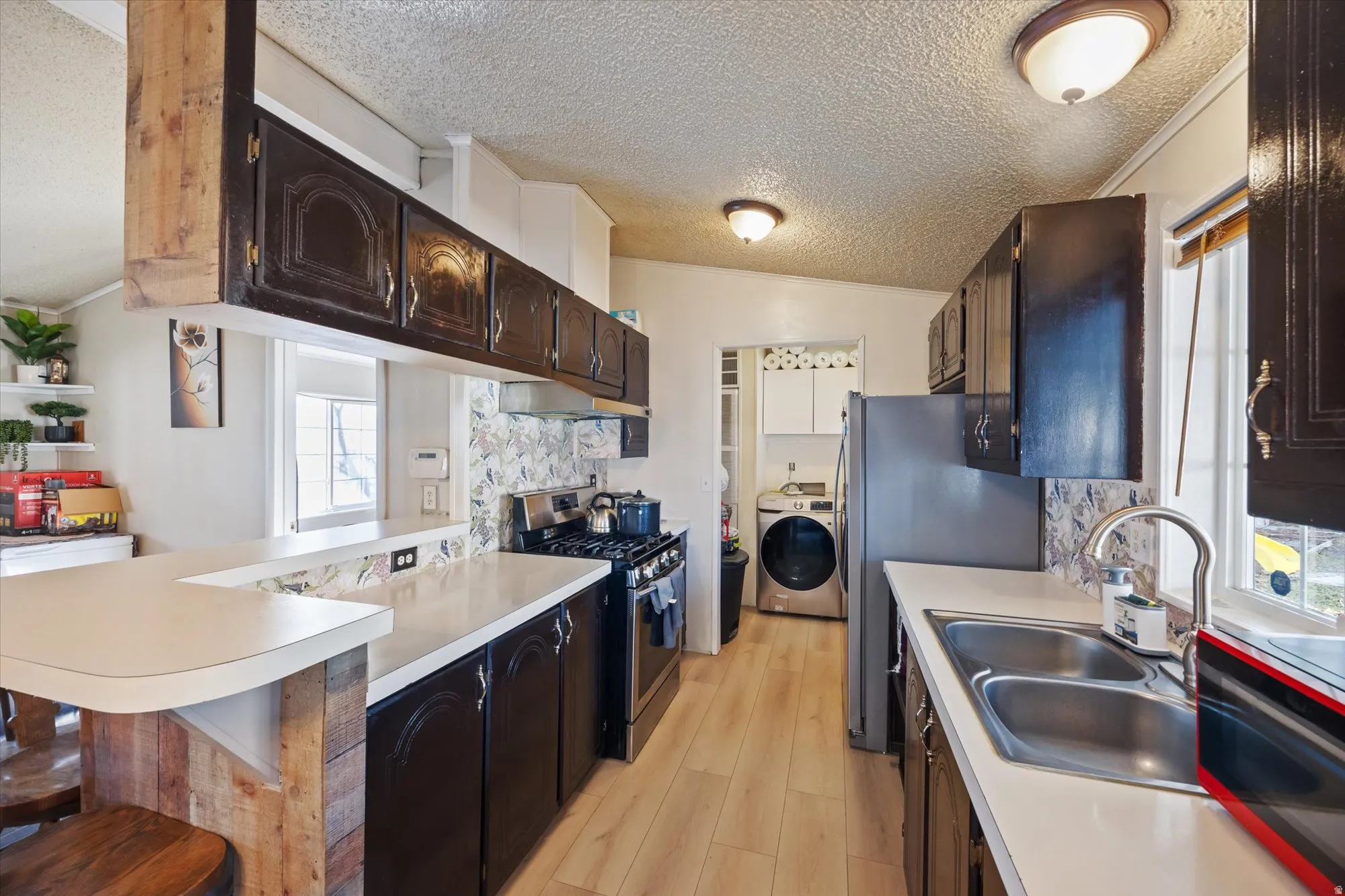 Kitchen featuring appliances with stainless steel finishes, a breakfast bar area, light countertops, plenty of natural light, and a textured ceiling