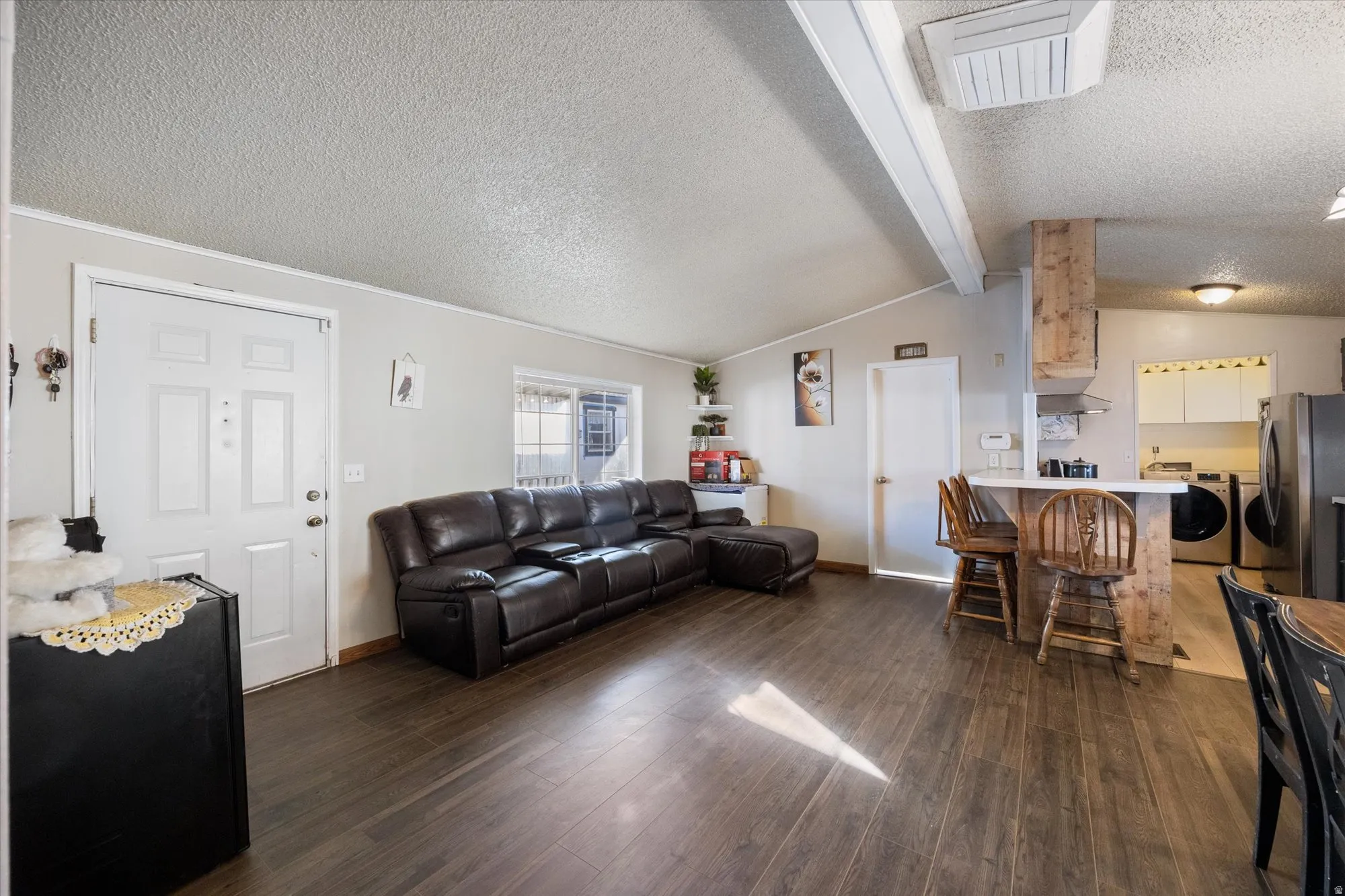 Living area featuring a textured ceiling, dark wood-style flooring, cooling unit, and separate washer and dryer