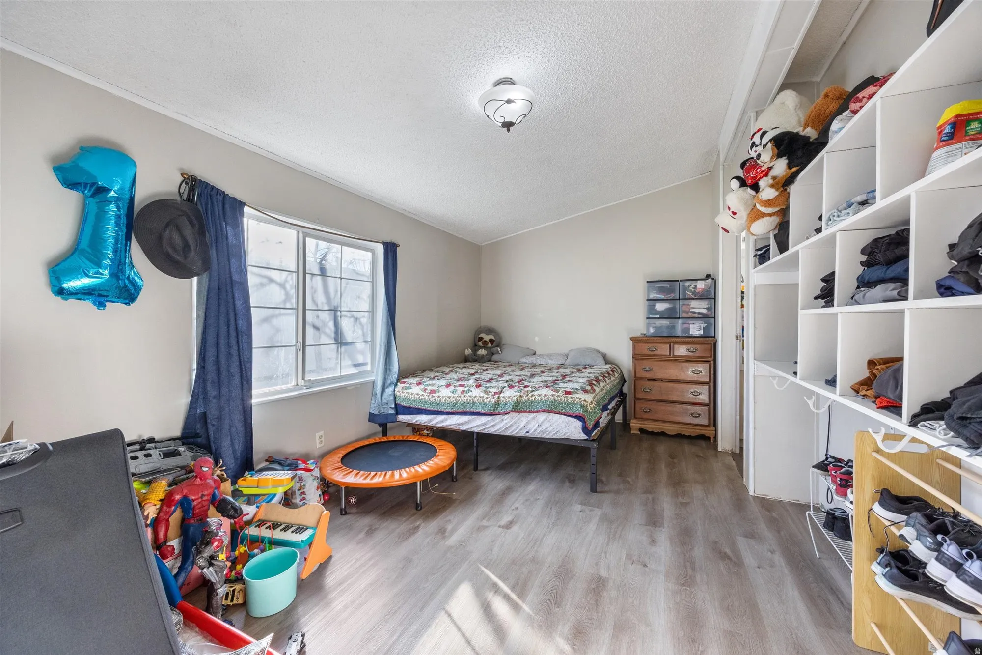 Bedroom featuring a textured ceiling, vaulted ceiling, and light wood-style floors