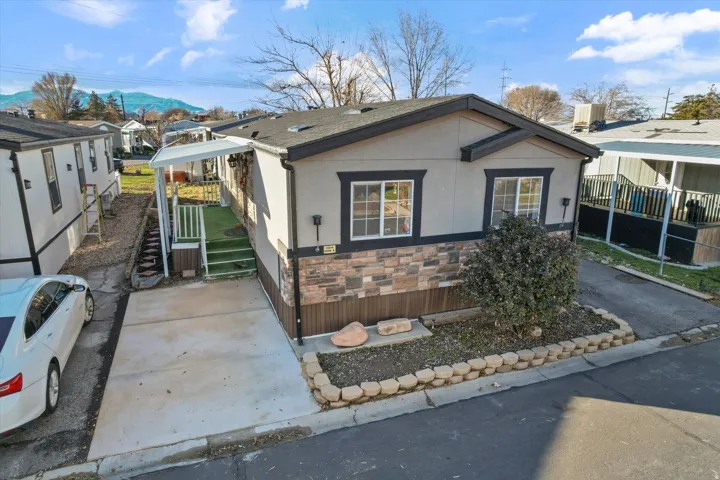View of front of property with stone siding, stucco siding, and a shingled roof