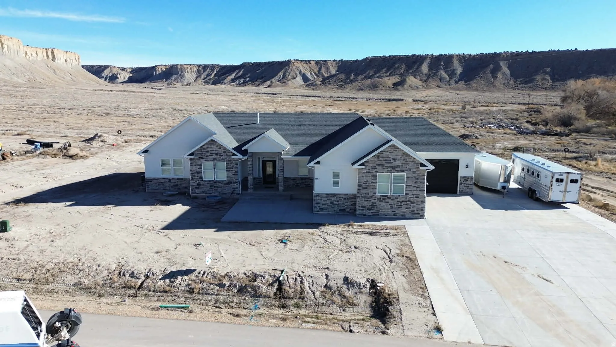 View of front of property with stone siding, driveway, a garage, and a mountain view
