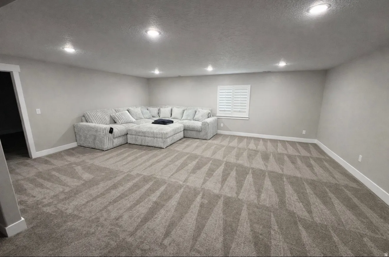 Unfurnished living room with a textured ceiling, recessed lighting, and light carpet